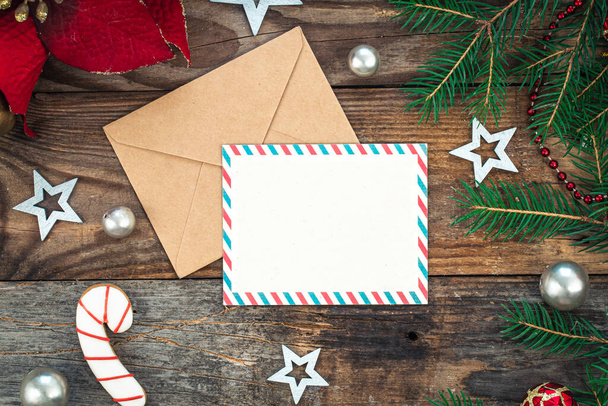 Blankopapier, Umschlag, Fichtenzweige und gemütliche Weihnachtsdekor-Details auf Holzgrund, flache Lage. - Foto, Bild