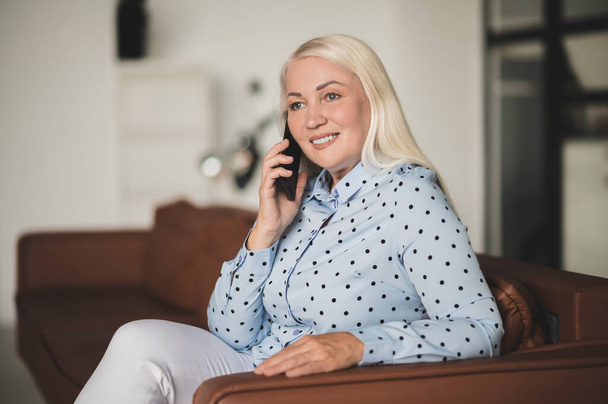 Work from home. Blonde woman talking on the phone and looking involved - Photo, Image