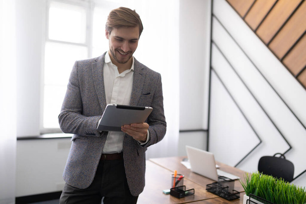 business man with a tablet in his hands IN A STYLISH OFFICE. - Photo, Image