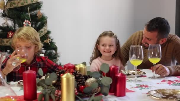 Felice famiglia caucasica con Babbo Natale cappelli ridere e celebrare la cena di Natale. Padre, madre, figlio e figlia. - Filmati, video