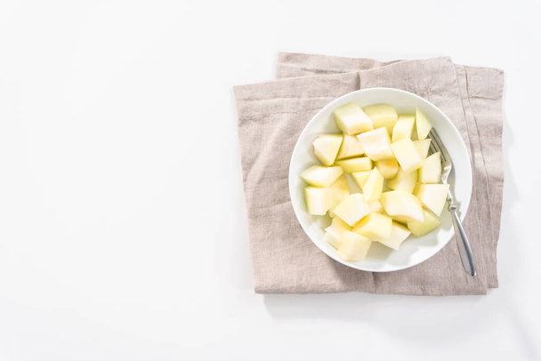 Flat lay. Sliced golden dewlicious melon in a white bowl. - Foto, Imagem