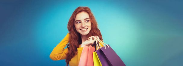 Vásárlás koncepció - portré fiatal, szép, vonzó redhair lány mosolyogva nézett kamera bevásárlószatyor közelről. Pasztell kék háttér. Másolja a hely. - Fotó, kép