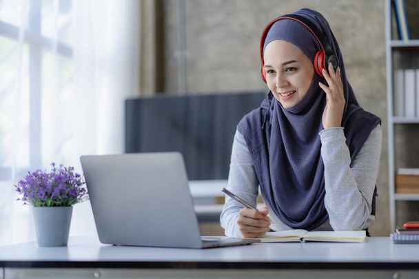 Musliminainen opiskelija hijabissa opiskelee verkossa kannettavan aasialaisen tytön kanssa kuulokkeissa tekemässä kotitehtäviä digitaalisen tabletin opettamisen kanssa verkossa Musliminainen opettaja tekee videopuhelun. - Valokuva, kuva
