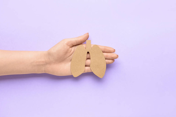 Female hand and paper lungs on lilac background - Photo, Image