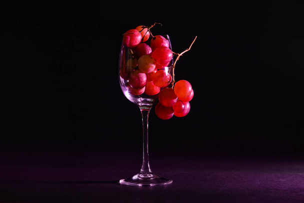 Stłuczone szkło z dojrzałymi winogronami na ciemnym tle - Zdjęcie, obraz