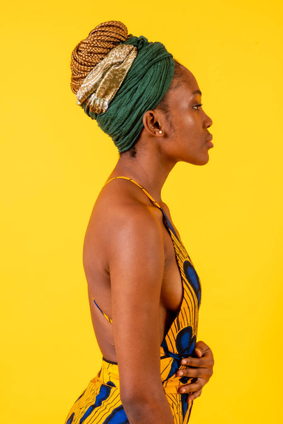 A person woman of black ethnicity with traditional costume on yellow background, profile model - Foto, Imagem