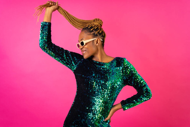 A black ethnic woman with braids dancing at party on a pink background - Фото, зображення