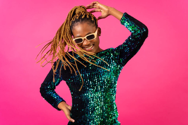 African young woman with party braids on a pink background, smiling having fun dancing - Fotoğraf, Görsel