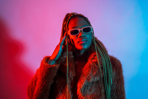 Black ethnic woman with braids with red and blue led lights, studio shoot with sunglasses - Φωτογραφία, εικόνα