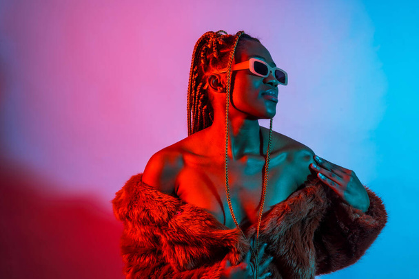 Attractive black ethnic woman with braids with red and blue led lights, urban studio shoot - Foto, Imagem