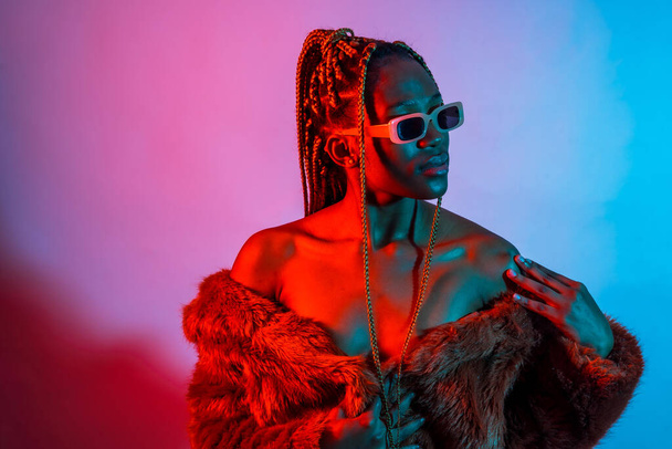 Attractive black ethnic woman with braids with red and blue led lights, urban studio shoot - Φωτογραφία, εικόνα