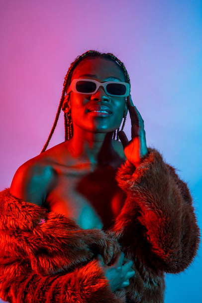 Attractive black ethnic woman with braids with red and blue led lights, trap dancer wearing sunglasses - Fotó, kép