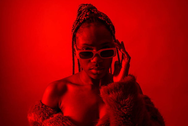 Attractive black ethnic woman with braids with red led lights, trap dancer with seductive look - Zdjęcie, obraz