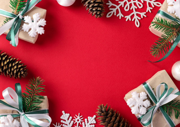 Рождественская рамка с подарками, конусами, снежинками на красном фоне. Рождественская открытка. С Новым годом - Фото, изображение