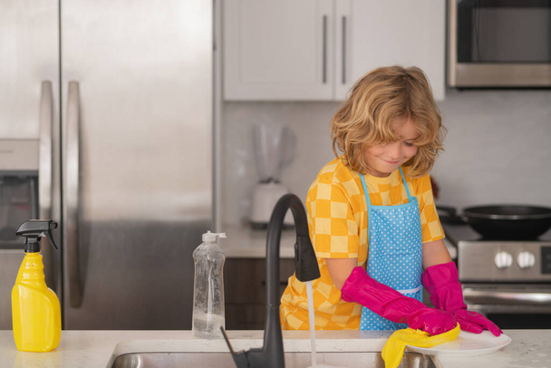 Little housekeeper. Child washing and wiping dishes in kitchen. American kid learning domestic chores at home. Kid cleaning to help parents with housework routine. Schoolboy housekeeping - Φωτογραφία, εικόνα