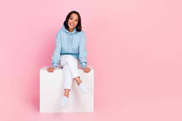 Full length photo of pretty adorable girl dressed blue sweatshirt having rest white cube chair empty space isolated pink color background. - 写真・画像