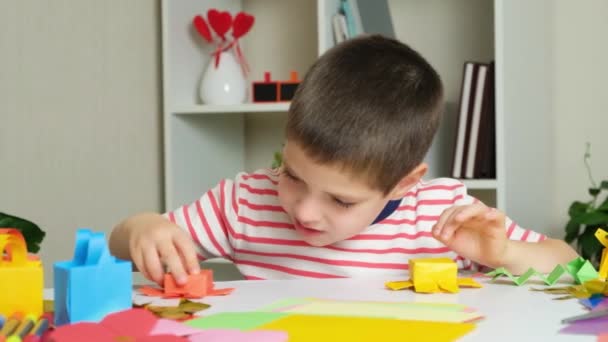 Un bambino gioca con statuette di polpo fatte di carta origami - Filmati, video