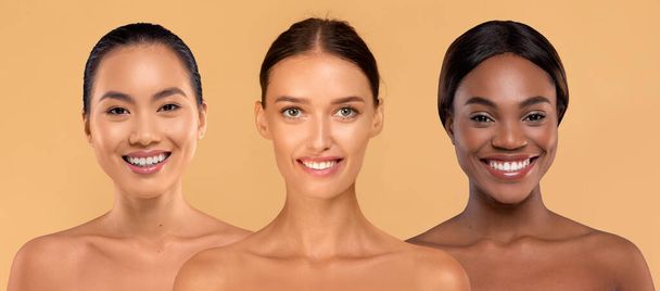 Tres atractivas señoritas multiculturales semidesnudas sonriendo a la cámara en un fondo beige de estudio, mostrando sus hermosas sonrisas y su perfecta piel lisa, collage, pancarta. Spa, concepto de bienestar - Foto, imagen