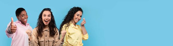 Multiracial young ladies gesturing on blue studio background, three attractive millennial women in casual showing various gestures and smiling, panorama with copy space, collage - Photo, Image