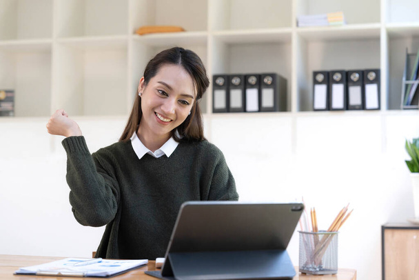 Pretty Asian businesswoman sitting on a laptop And the work came out successfully and the goal was achieved, happy and satisfied with her - 写真・画像