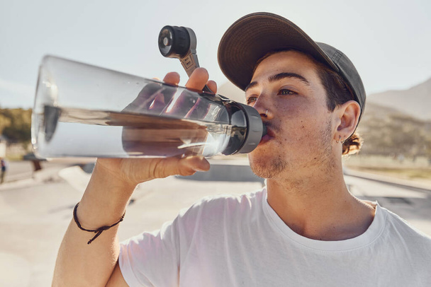 Man, water bottle and outdoor closeup for hydration, fitness and workout in summer sunshine. Guy, drinking and water for exercise, training and wellness on break, relax or rest in urban park in sun. - Foto, imagen