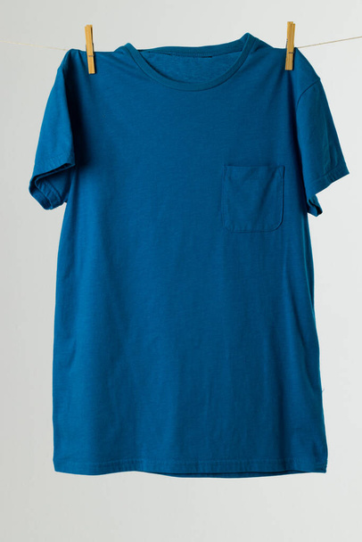 Close up of hanging blue tshirt and copy space on white background. Clothing, fashion and retail concept. - Foto, Imagen