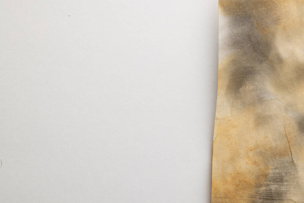 Burned and stained piece of paper with copy space on white background. Abstract paper texture background and communication concept. - Fotó, kép
