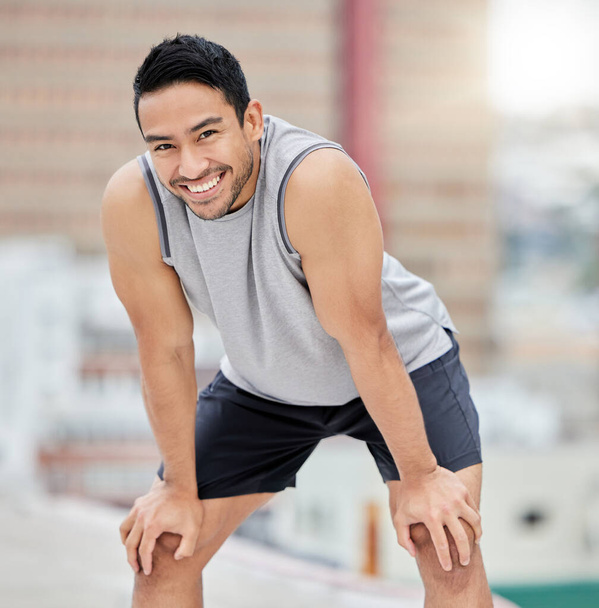Tired, fitness and man rest on roof in city after outdoor sports workout, health motivation and training outside. Blurred cityscape background, urban athlete and personal trainer rest after exercise. - Photo, image