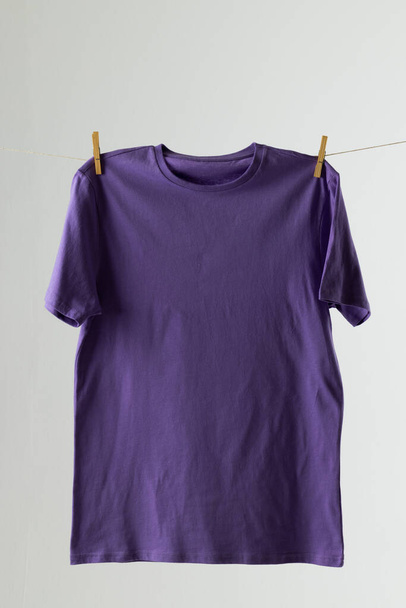 Close up of hanging purple tshirt and copy space on white background. Clothing, fashion and retail concept. - Foto, immagini