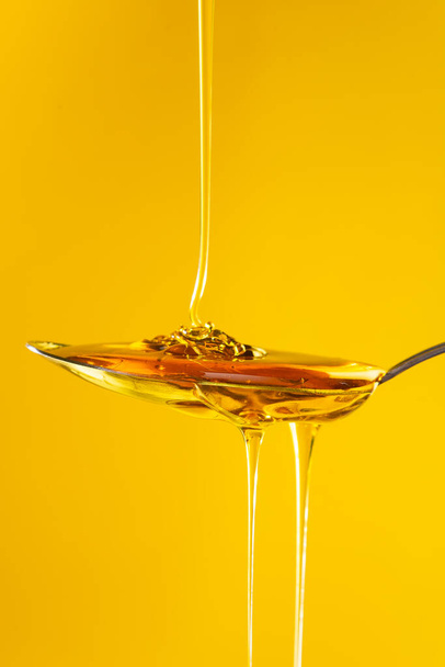 honey drizzling onto a spoon  - Fotografie, Obrázek