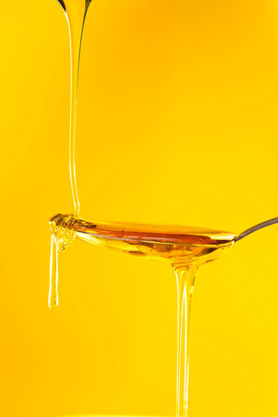 honey drizzling onto a spoon  - Foto, afbeelding