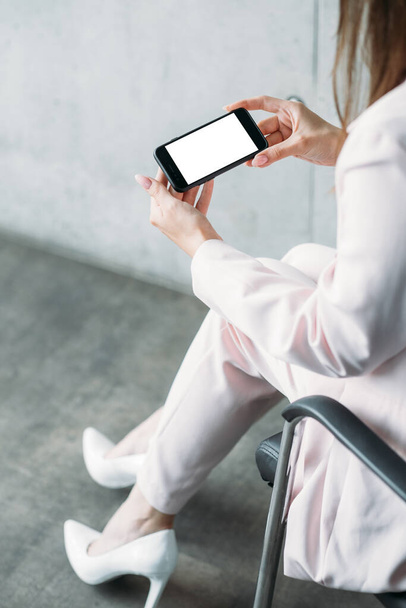 Mobile connection. Digital mockup. Business work. Elegant woman holding smartphone blank screen sitting chair in light room interior. - 写真・画像
