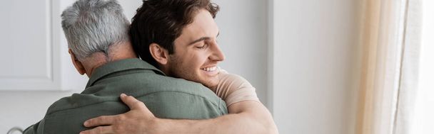 heureux jeune homme embrassant mature et gris père à la maison, bannière - Photo, image