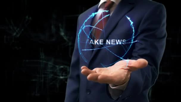 Businessman shows concept hologram Fake news on his hand. Man in business suit with future technology screen and modern cosmic background - Footage, Video