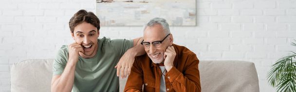 veselý mladý muž usmívá s vousatým a zralým otcem v brýlích, prapor - Fotografie, Obrázek