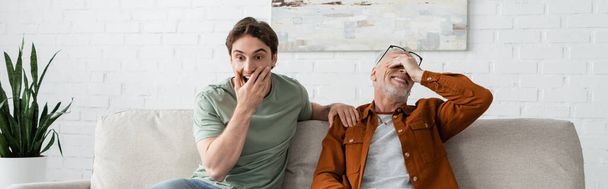 surprised young man covering mouth near smiling mature father in eyeglasses, banner  - Foto, Imagem