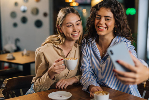 Two young woman take photos in a cafe - Foto, Imagen
