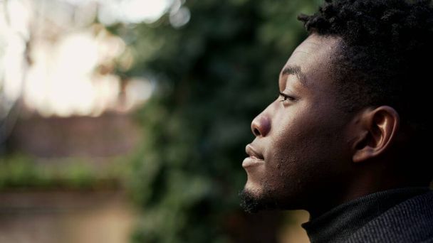 Thoughtful black African man looking up at sky closing eyes in contemplation - 写真・画像