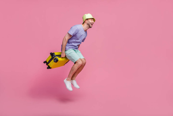Full size photo of handsome young guy jump look empty space travel agency client dressed trendy blue look isolated on pink color background. - Foto, imagen