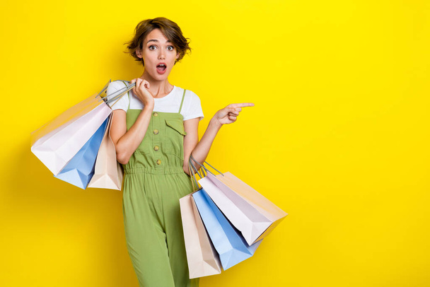 Photo of impressed shocked shopaholic girl hold much package with clothes gifts big sale finger point mockup isolated on yellow color background. - Fotoğraf, Görsel