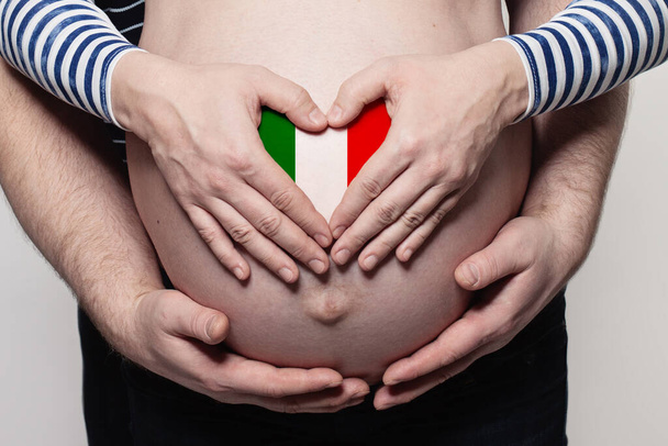 Italiaans familieconcept. man omarmen zwangere vrouw buik en hart met vlag van Italië kleuren closeup - Foto, afbeelding