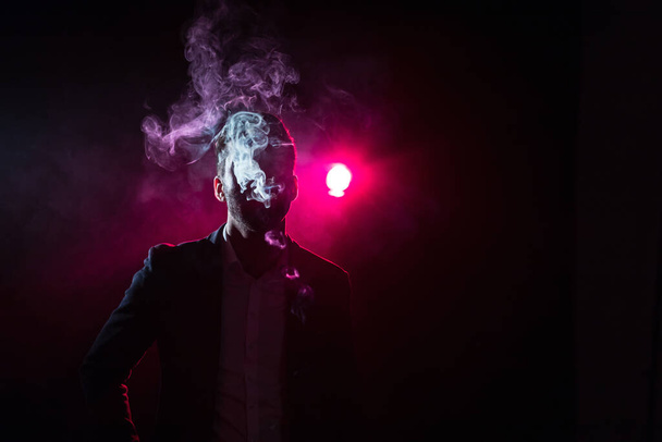 Photo of man in smoke on black and pink background. Concept of male model. - Zdjęcie, obraz