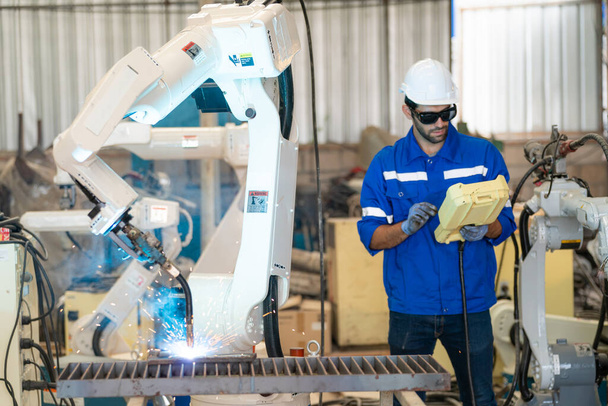 Robotics engineer working on maintenance of modern robotic arm in factory warehouse - Photo, Image