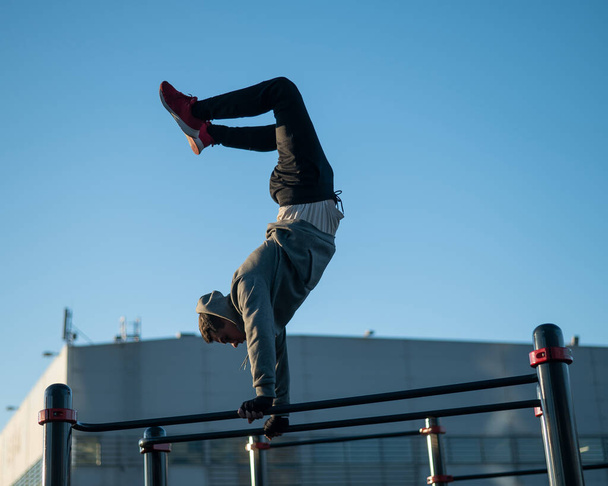 Young caucasian man doing parallel bars exercise outdoors - Φωτογραφία, εικόνα