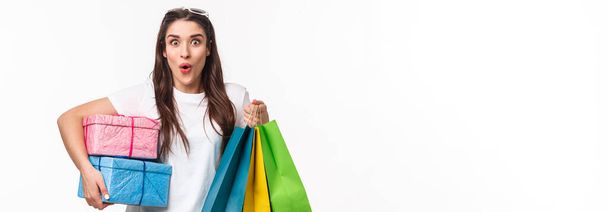 Shopping, holidays and lifestyle concept. Portrait of excited, amused young girl hurry up and buying presents, last days of promo offer discounts, holding gifts and shop bags. - Photo, Image