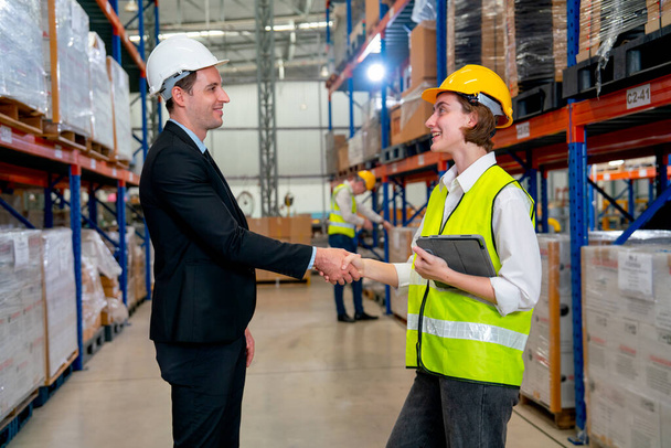 Warehouse manager shake hands with his warehouse member in the team and they look to each other and express happy to work together in workplace. - Foto, Imagem
