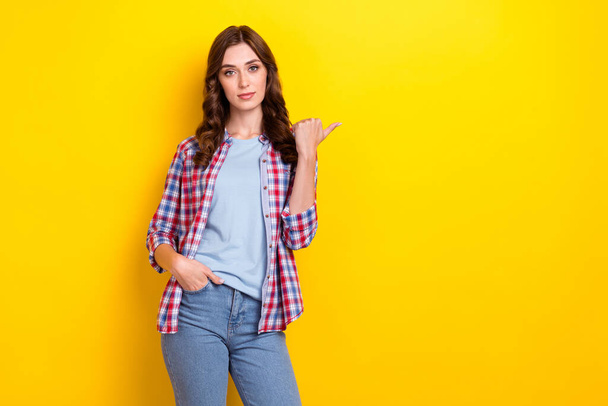 Photo of good mood cute lady wear plaid shirt pointing finger empty space isolated yellow color background. - Zdjęcie, obraz