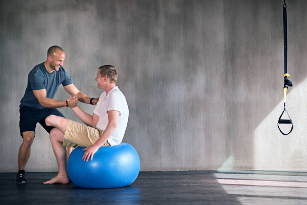 Świetna robota. fizjoterapeuta i jego pacjent ćwiczący na szwajcarskiej kuli - Zdjęcie, obraz