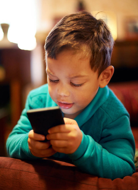 Elbűvölte a technológia. Egy kisfiú játszik egy mobiltelefonnal. - Fotó, kép