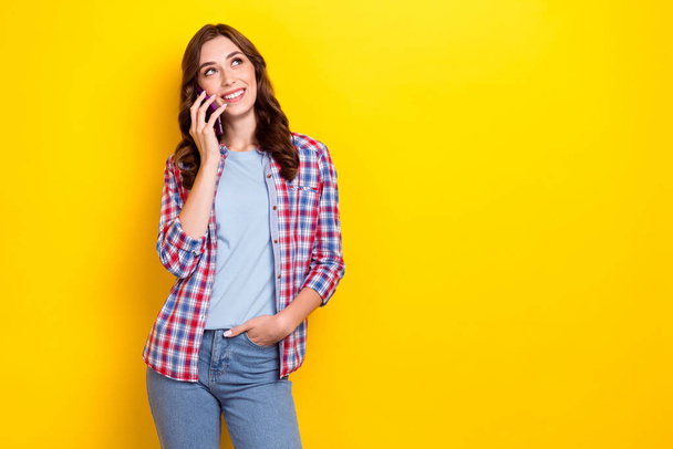 Photo of young dreaming lady wear checkered shirt talking conversation look empty space advertisement eshopping isolated on yellow color background. - Foto, immagini